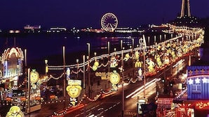 Eine gut beleuchtete Straße mit leuchtenden Schildern und einem Riesenrad im Hintergrund.