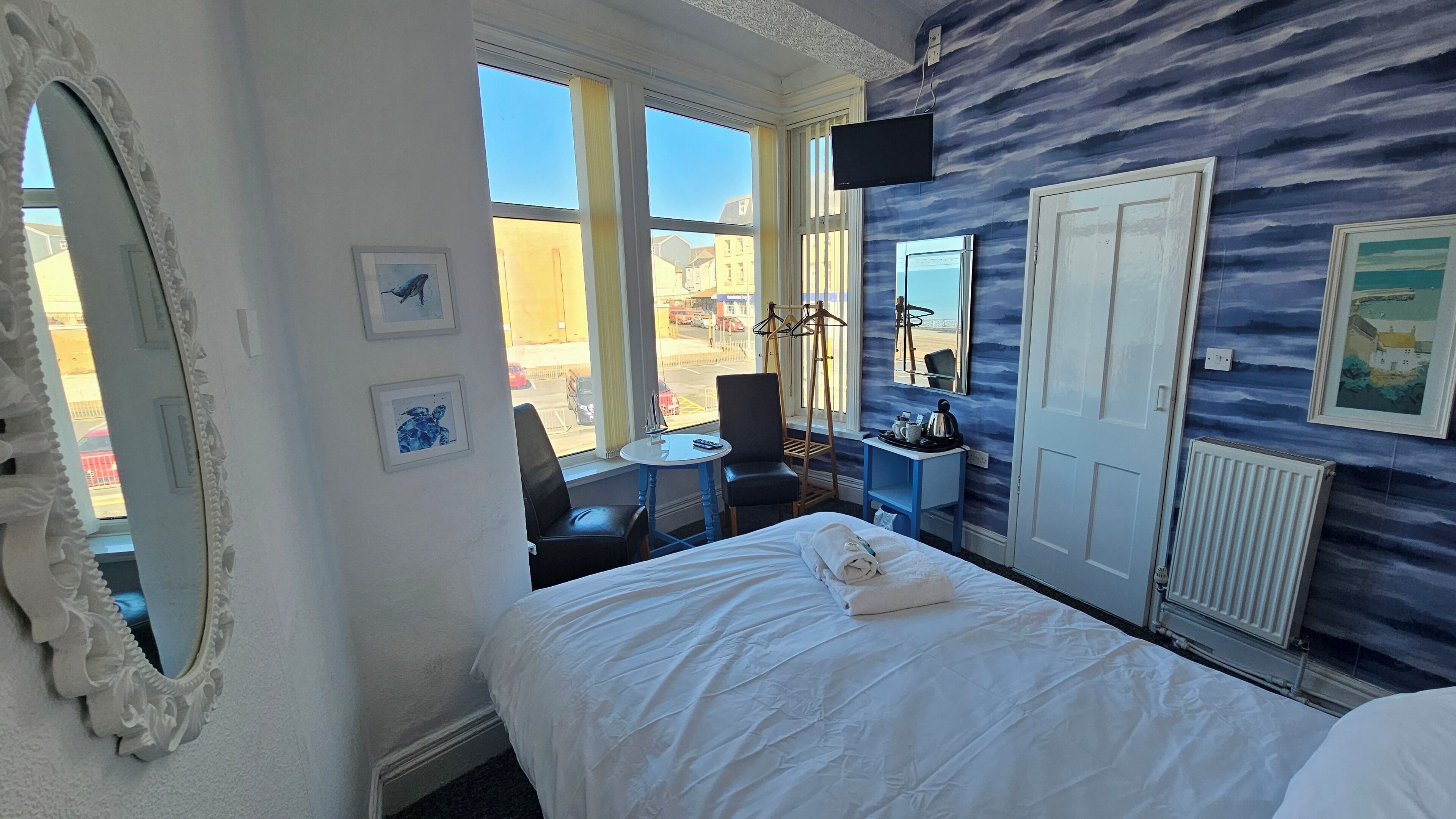 Una habitación de hotel con cama, escritorio, silla, ventana y puerta.