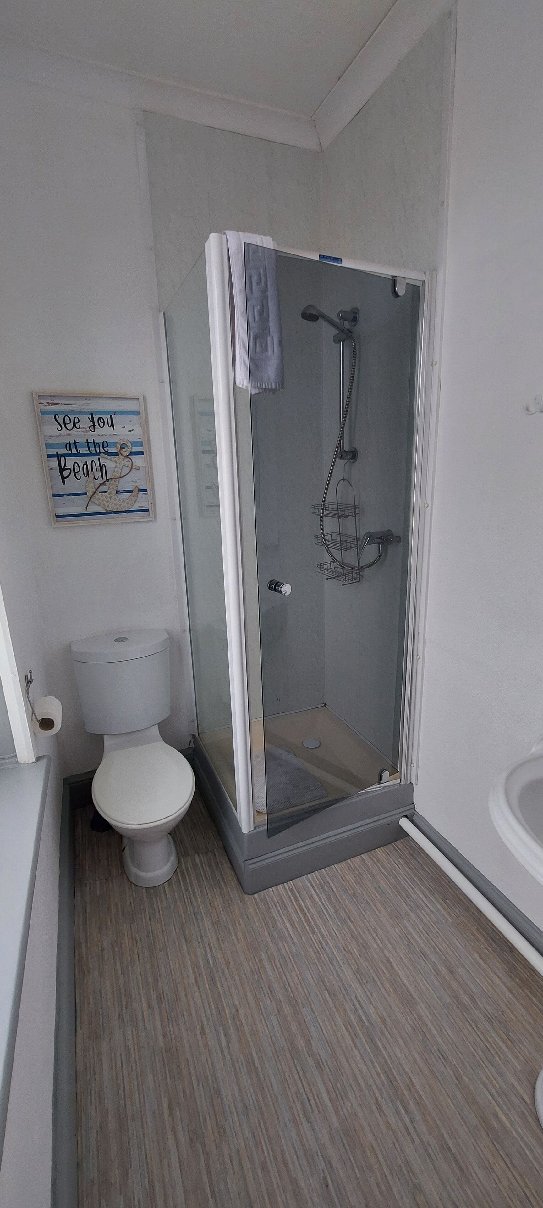 Un baño con inodoro, cabina de ducha y lavamanos.
