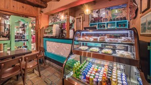 A café with wooden furniture, a display case with food items, and a beverage cooler.