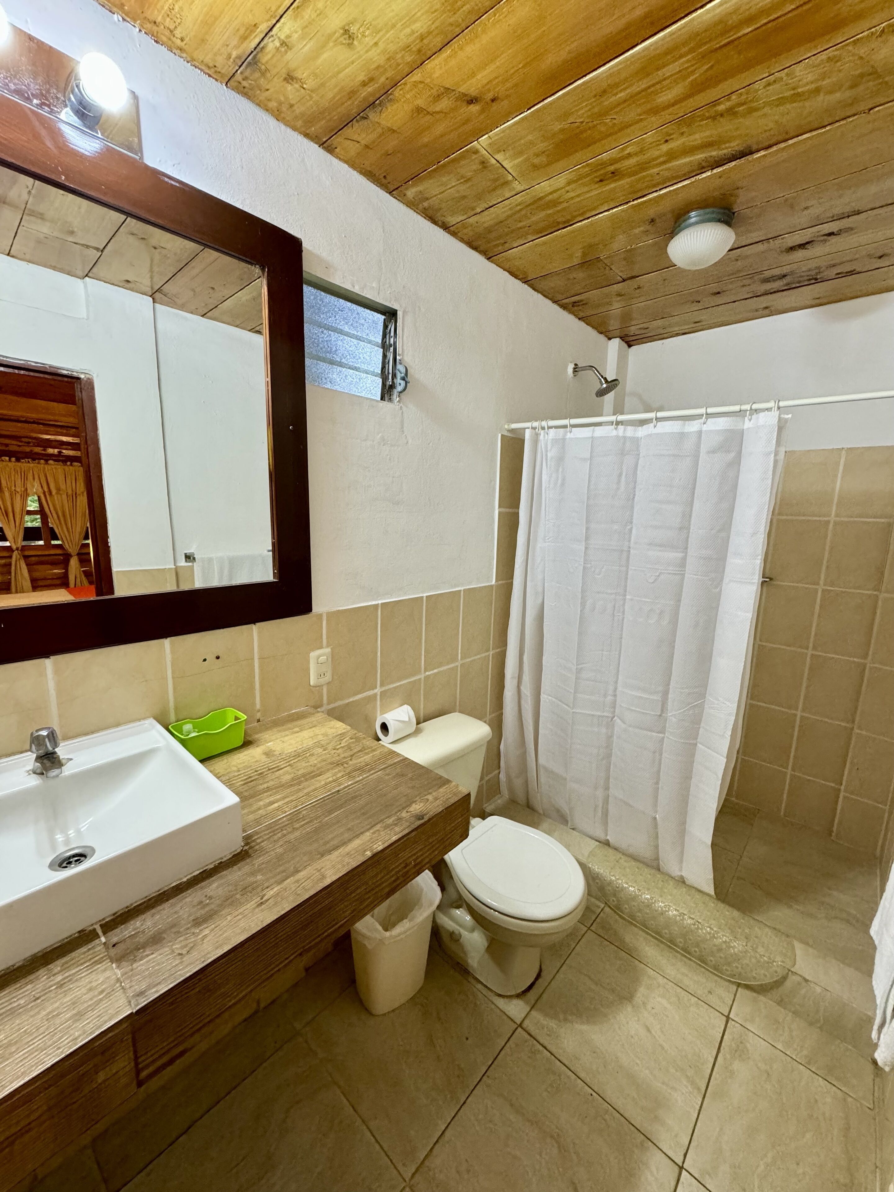 A bathroom with a wooden vanity, a sink, a toilet, and a shower curtain.