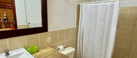 A bathroom with a wooden vanity, a sink, a toilet, and a shower curtain.