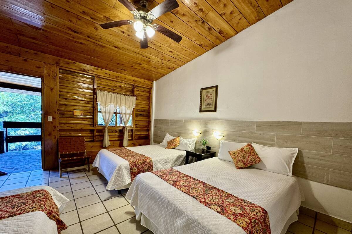 Habitación con dos camas, techo de madera y vistas al exterior.