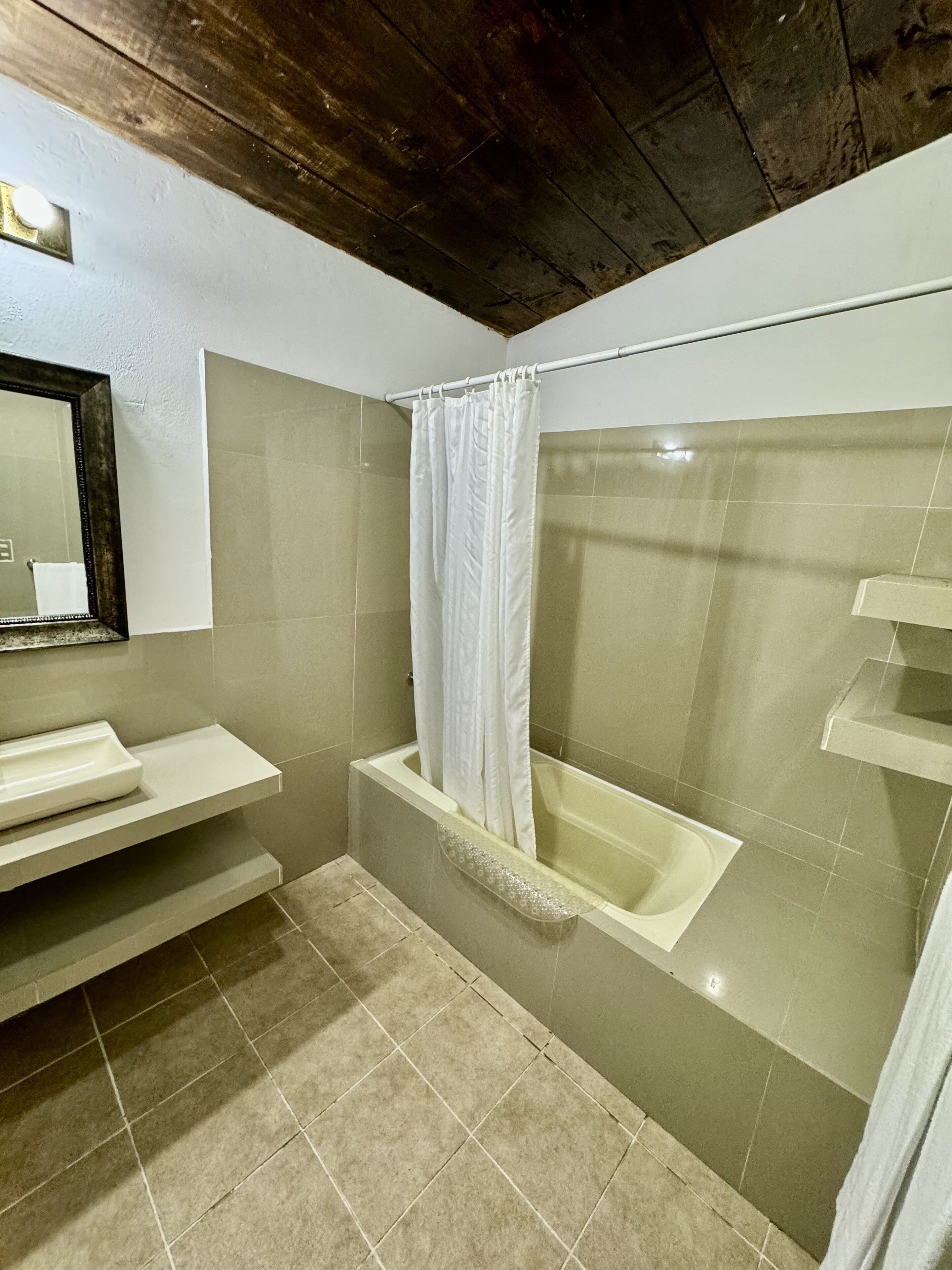A bathroom with a bathtub, a shower curtain, and a mirror.
