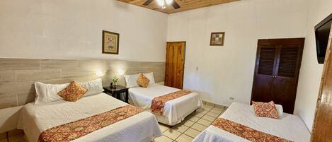 A hotel room with two beds, wooden ceiling, tiled floor, and a ceiling fan.
