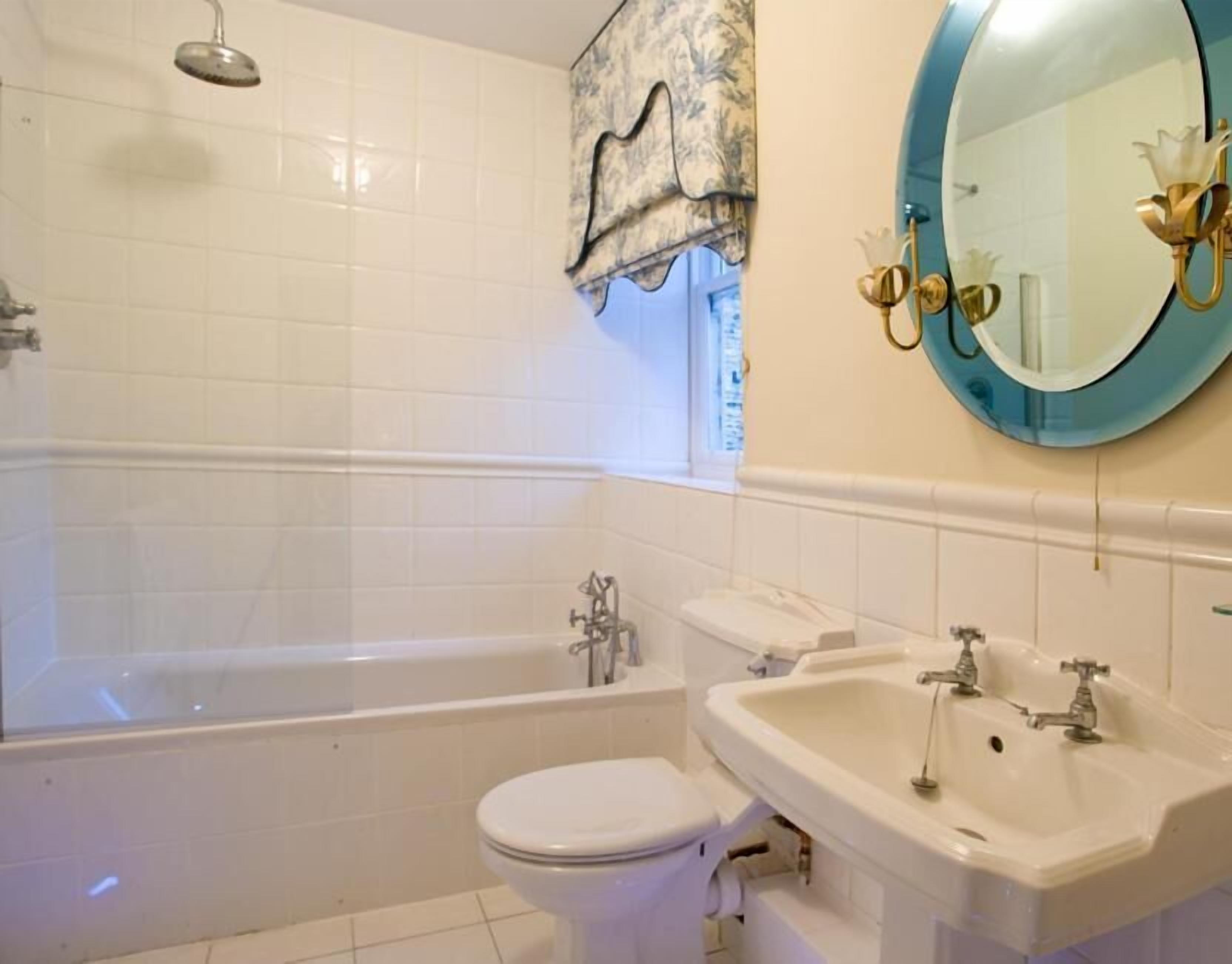 A bathroom with a bathtub, toilet, sink, and a large mirror.