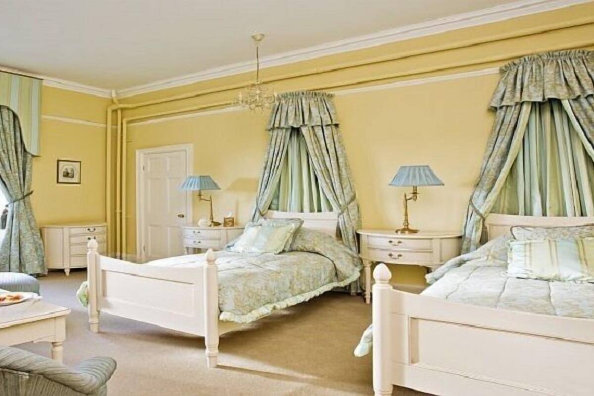 Ein Schlafzimmer mit zwei Betten, einem Sessel, einem Tisch und einem Heizkörper.