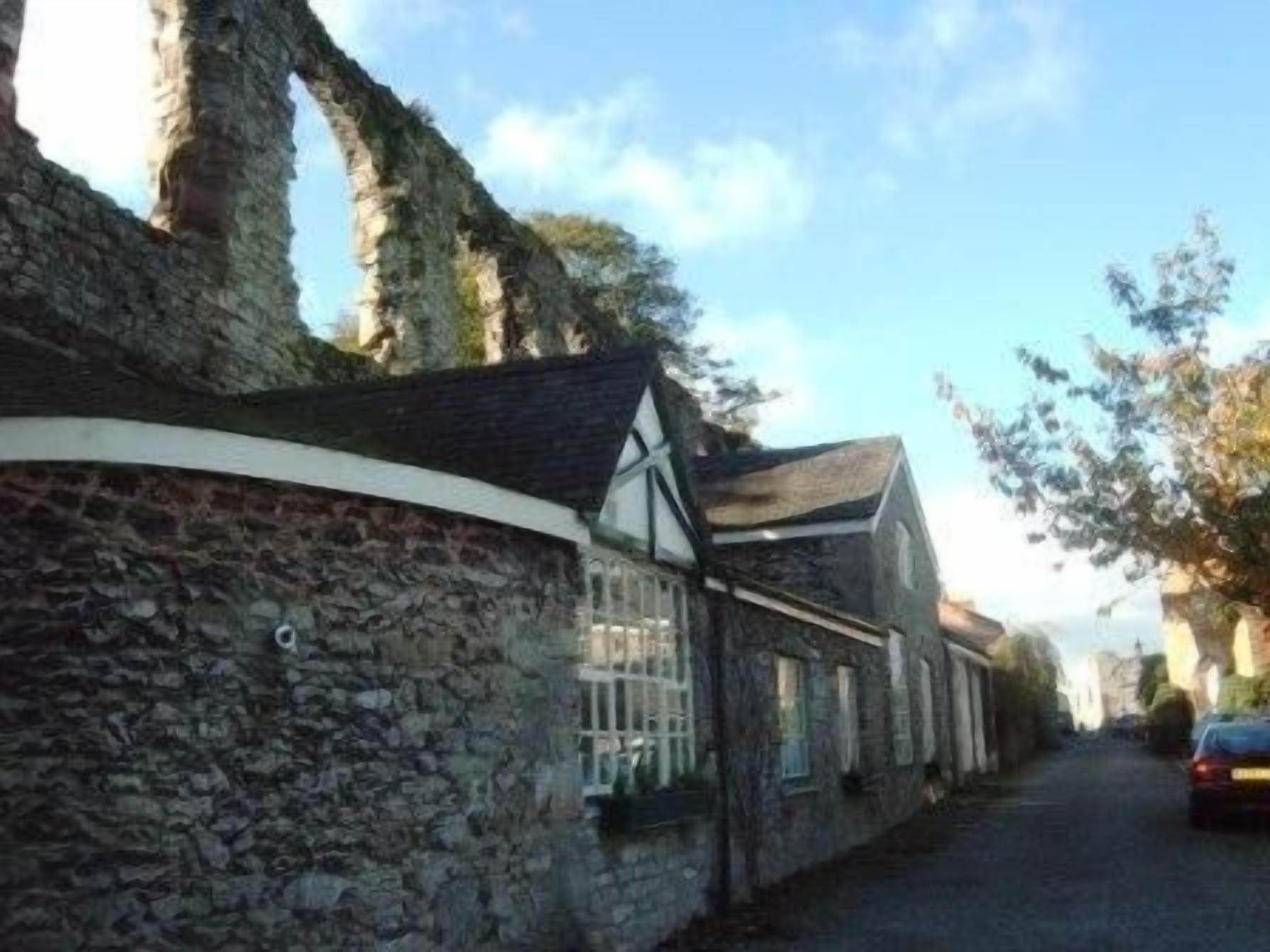Una calle estrecha con muros de piedra y edificios tradicionales de entramado de madera.