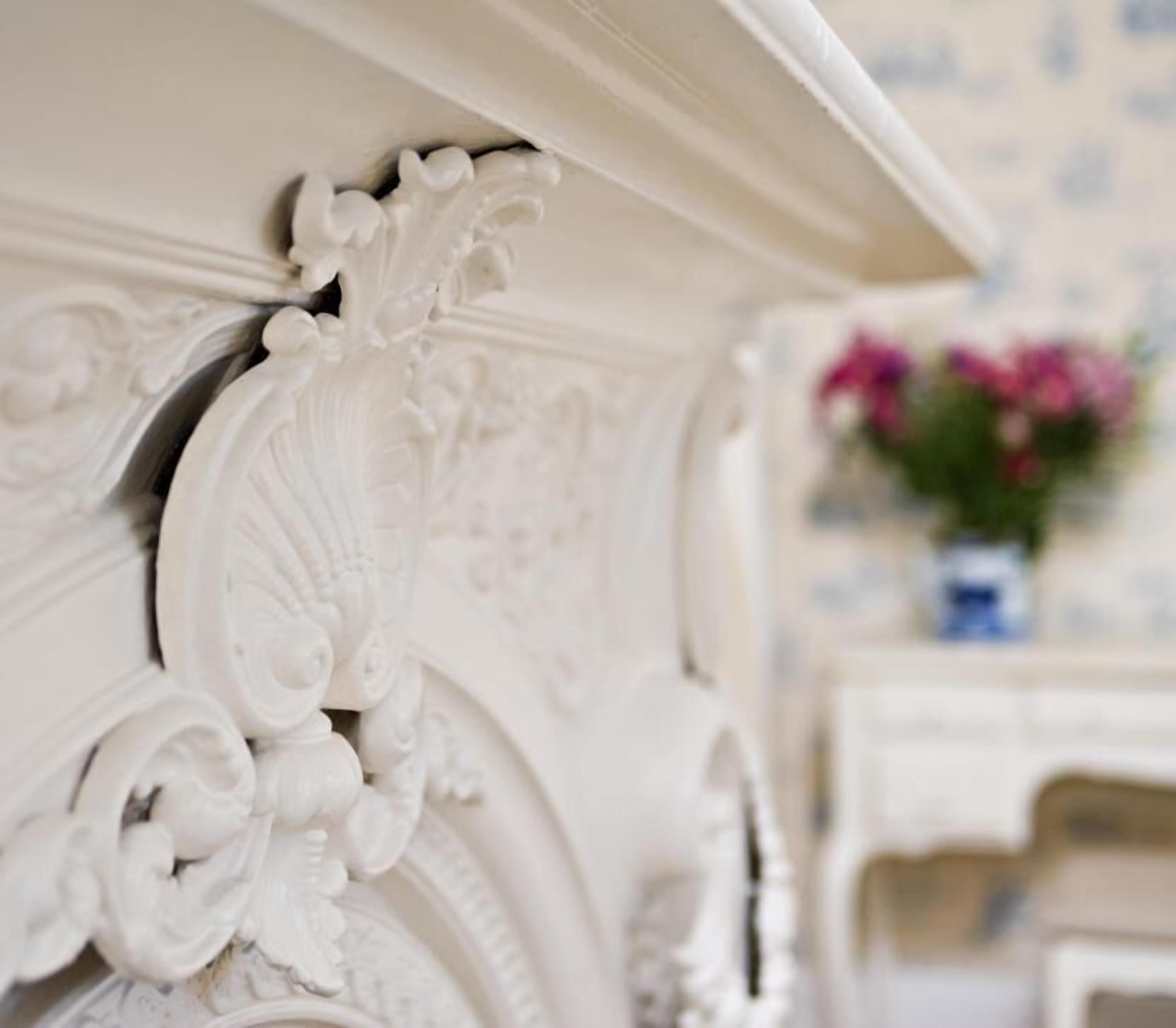 A close-up of a white ornate furniture piece with intricate carvings.
