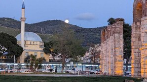 Una mezquita con cúpula y minarete, rodeada de ruinas antiguas y un aparcamiento.