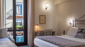 A hotel room with two beds, a desk, a chair, a ceiling fan, and a view of a pool and balcony. - Hotel Il Tiglio (Castel di Sangro)