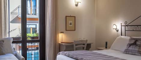 A hotel room with two beds, a desk, a chair, a ceiling fan, and a view of a pool and balcony.