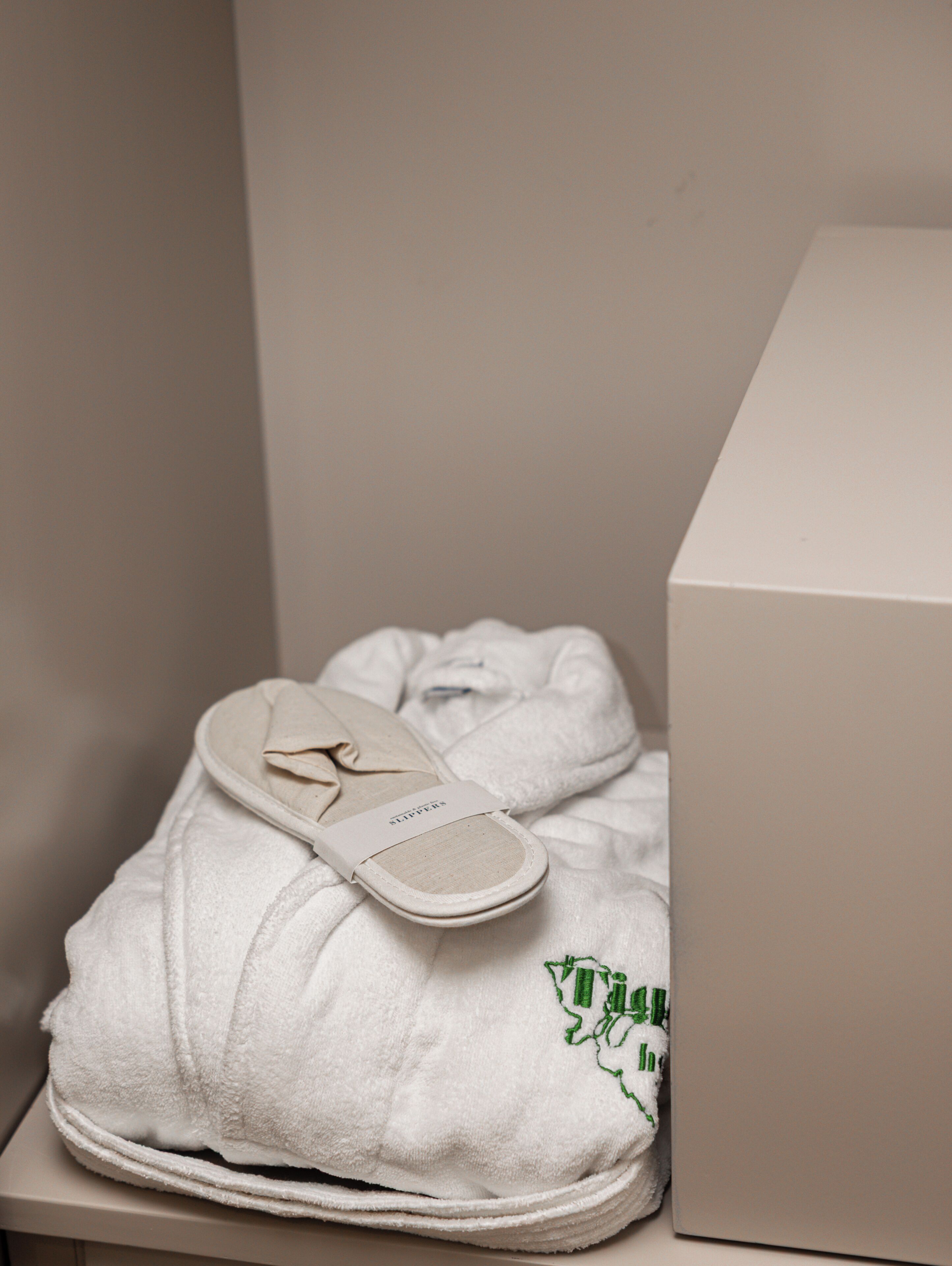 Une paire de pantoufles blanches, avec une étiquette, et une boîte blanche.