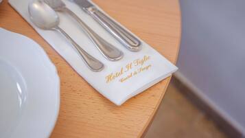 Une table dressée avec soin, avec une serviette blanche, une cuillère et une fourchette, le tout posé sur une table en bois.
