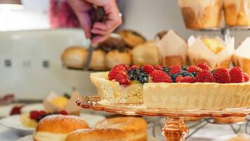A buffet with various pastries and a person serving food.