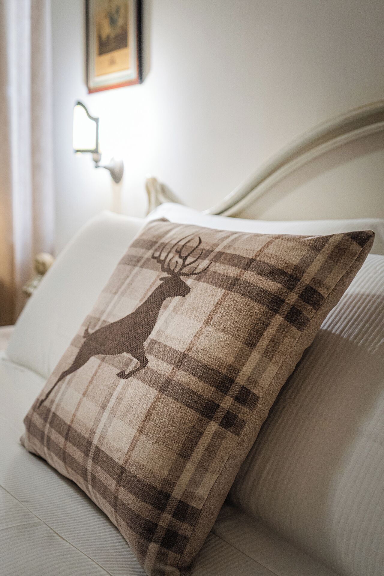 A bed with a plaid pillow featuring a deer design.
