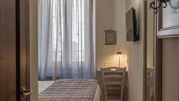 Een slaapkamer met een bed, een stoel, een bureau, een lamp en een spiegel.