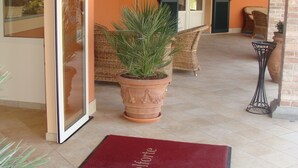 L’entrée d’un hôtel, avec un tapis rouge, des meubles en osier et une grande plante en pot.