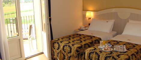 Ein Hotelzimmer mit zwei Betten, einem Balkon und einem Frühstücksbrettchen auf dem Bett.