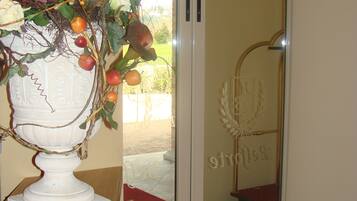 A room with a white vase of flowers on a wooden table, a sliding glass door, and a red carpet.