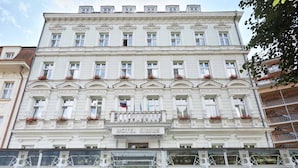 A multi-story hotel with a classical facade, large windows, and a sign indicating it is a hotel. - Park Spa Hotel Sirius (Karlovy Vary)