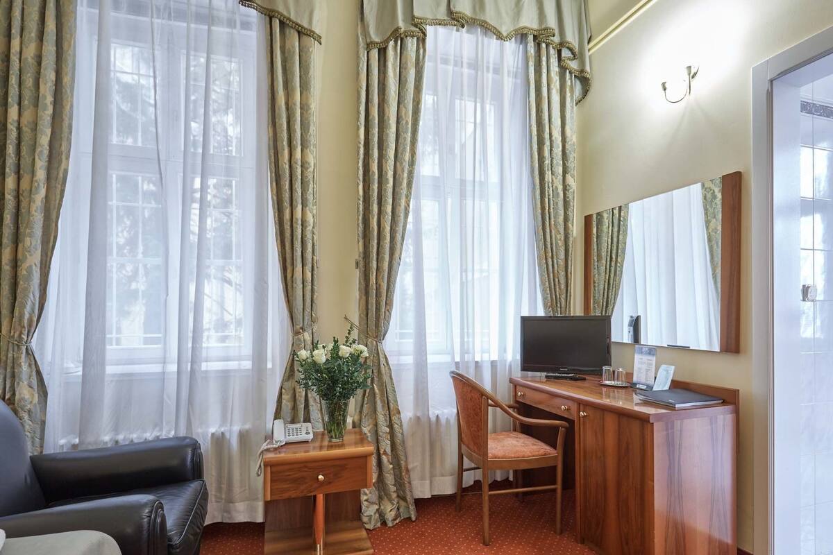 Habitación de hotel con un escritorio de madera, una silla, un televisor y un teléfono.