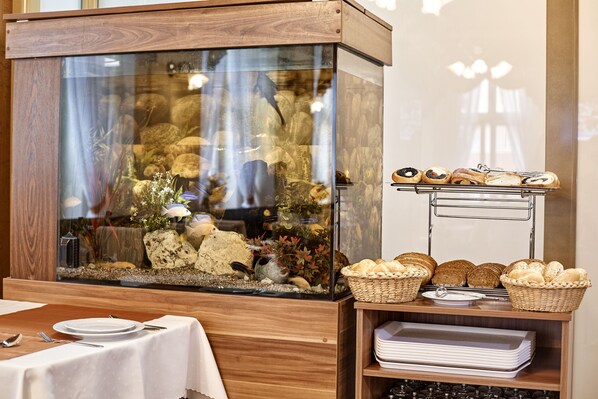 A dining area with a fish tank, bread baskets, and a buffet setup.