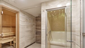 A modern bathroom with a glass-enclosed shower, a wooden sauna bench, and marble walls. - Park Spa Hotel Sirius (Karlovy Vary)