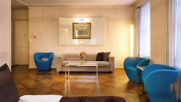 Uma sala de estar moderna com um sofá, duas poltronas azuis, uma mesa de centro e um quadro na parede.