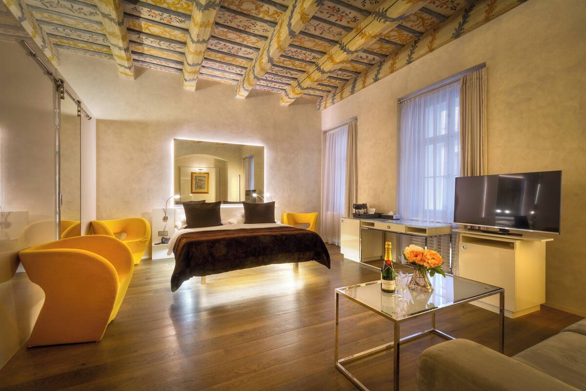 Une chambre d’hôtel moderne avec un grand lit, une télévision, une table basse en verre et un coin repas.