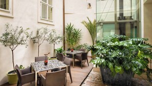 A covered patio with a table and chairs, potted plants, and a stone floor. - Hotel Three Storks (Prague)