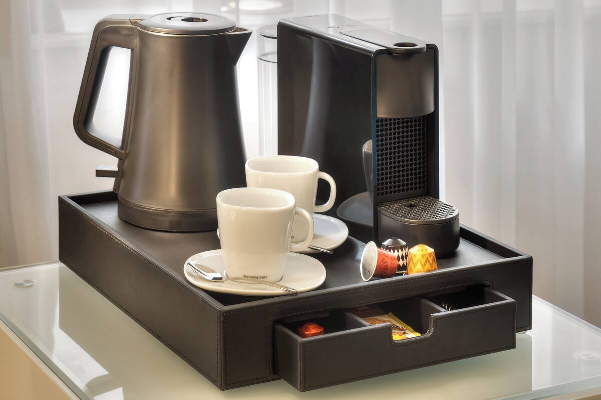 Un coin café équipé d’une machine à café, de deux tasses, d’une bouilloire et d’un plateau.