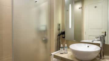 A modern bathroom with a glass shower enclosure, a white sink, and a large mirror.