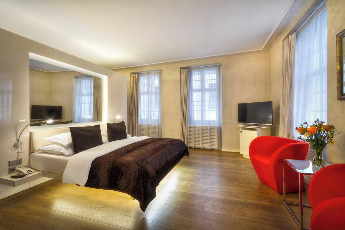 Une chambre d’hôtel avec un lit, une télévision, un bureau et une chaise rouge.