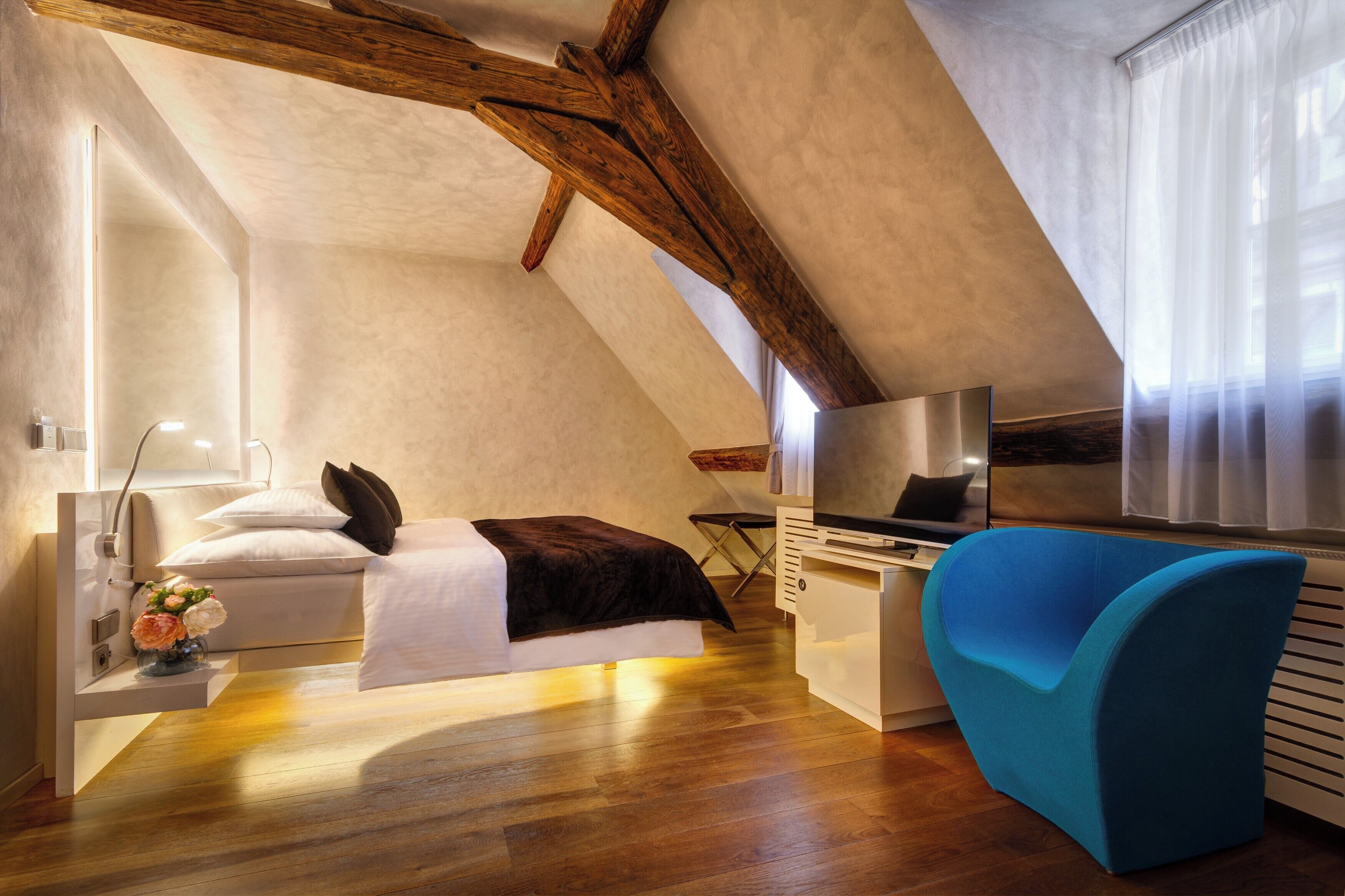 A bedroom with a bed, a desk, a chair, and a window with curtains.