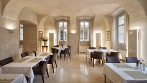 A dining area with tables set for two, arched ceilings, and large windows with curtains. - Hotel Three Storks (Prague)