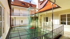 A glass-enclosed balcony with a metal railing, a tiled roof, and a clear sky. - Hotel Three Storks (Prague)