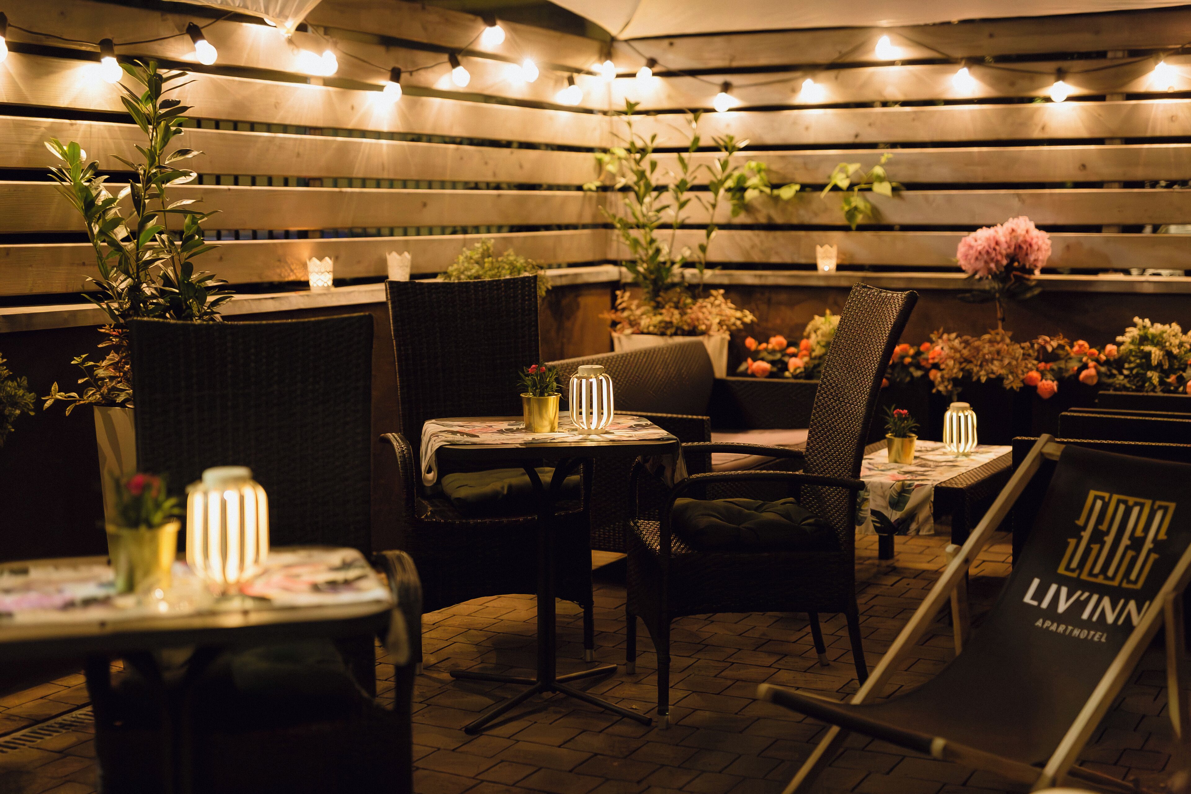 An outdoor dining area with wicker furniture, candles, and potted plants.