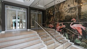 A staircase with a glass railing, leading to a room with a tropical mural. - Liv'Inn Aparthotel (Kraków)