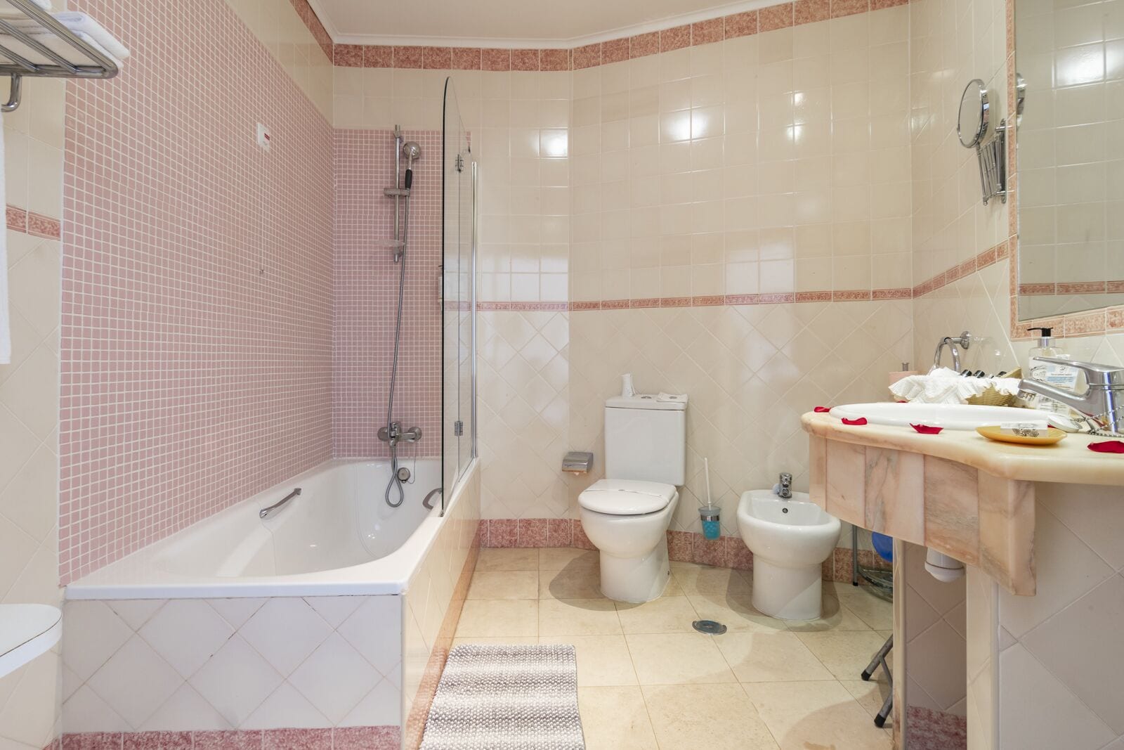 A bathroom with a bathtub, toilet, bidet, and a sink with a mirror.