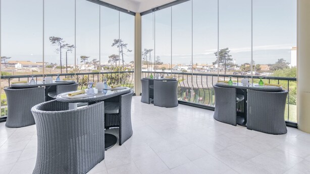 Un balcón con mobiliario de mimbre y vistas de la ciudad.