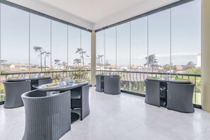 A balcony with wicker furniture and a view of the city. - Hotel Dom Vasco (Sines)