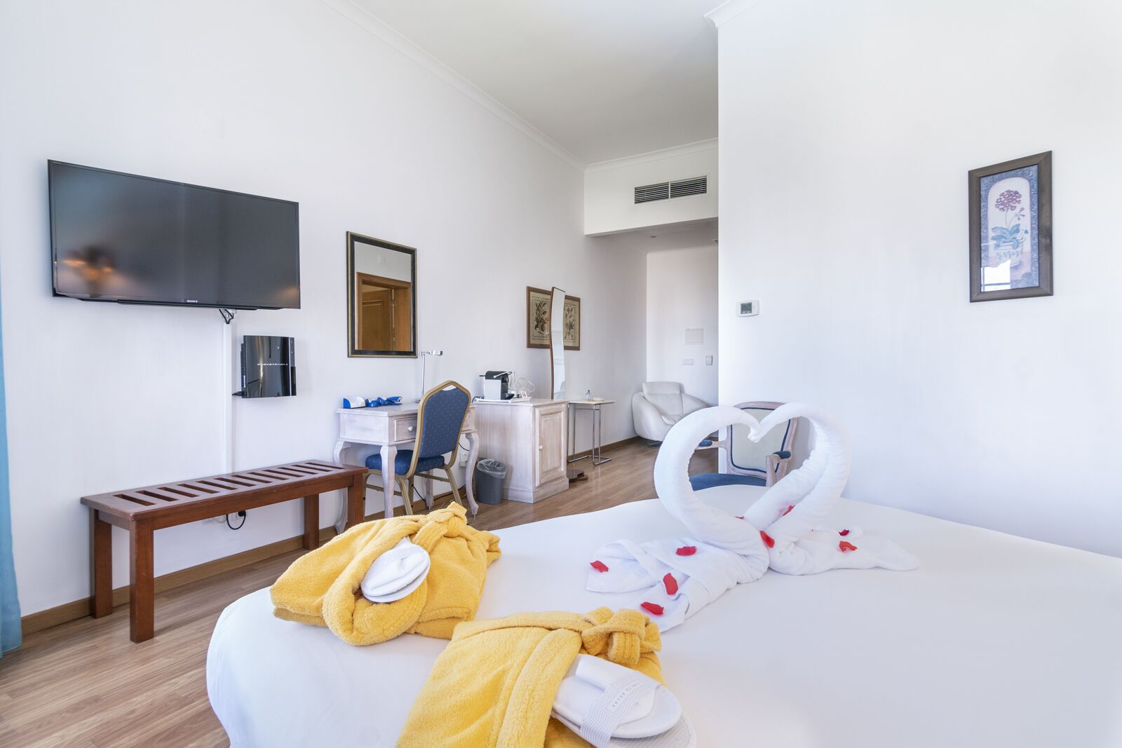 A hotel room with a bed, a desk, a chair, a TV, and a bathroom.