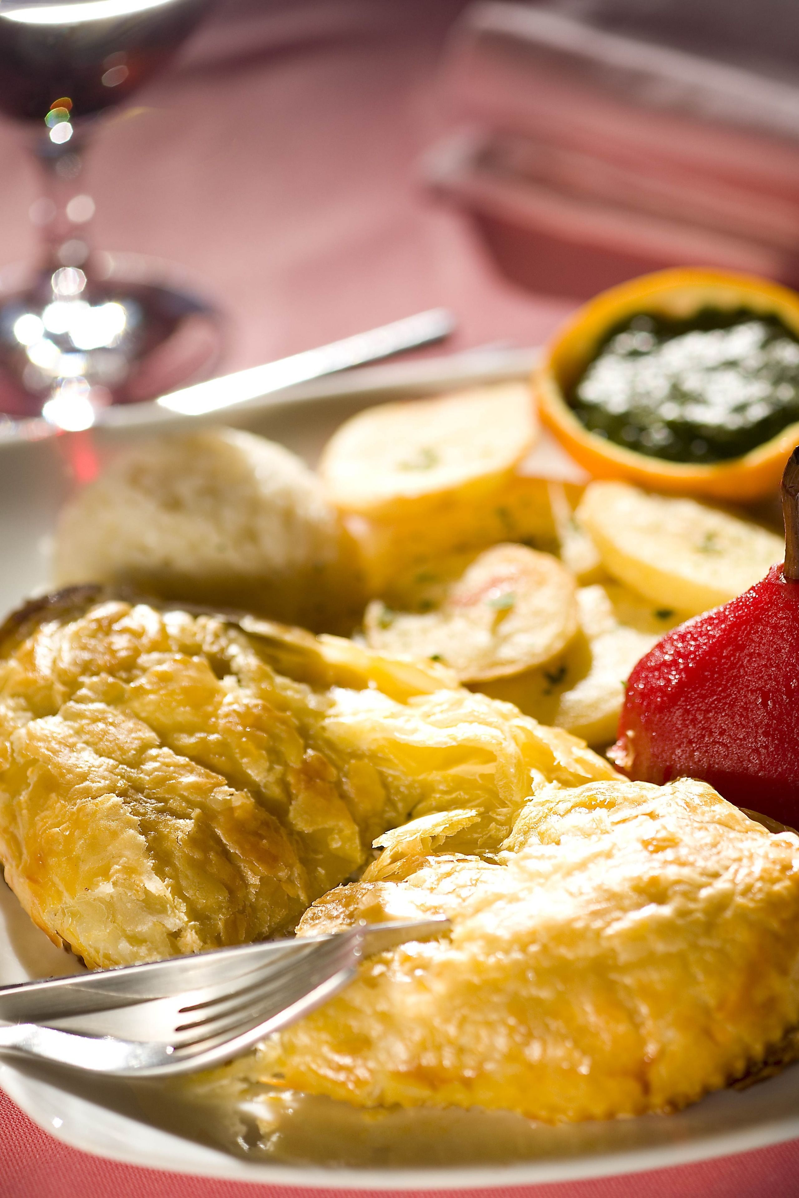 A plate with food items including a pastry, sliced potatoes, and a fruit.