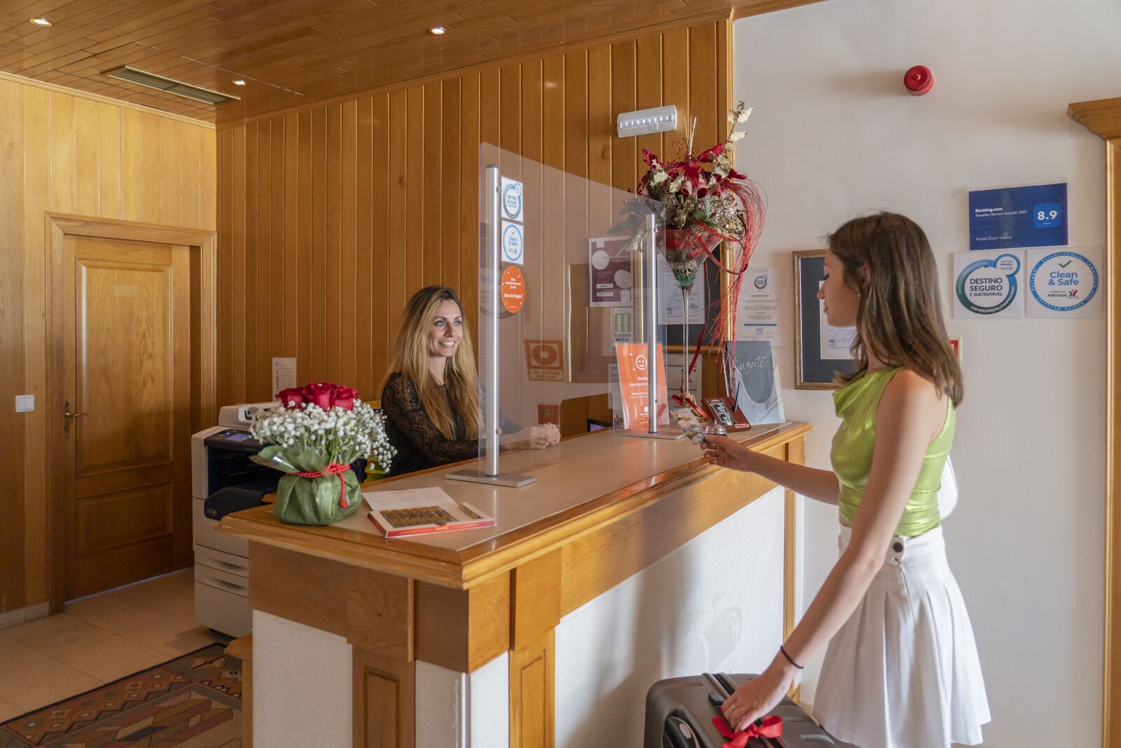 Un mostrador de recepción con un panel de madera, una vitrina de vidrio y un ramo de flores.