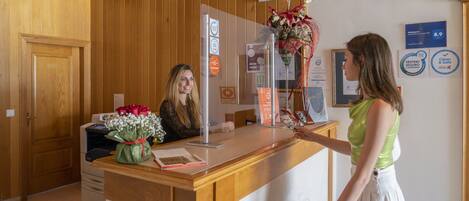 Un mostrador de recepción con un panel de madera, una vitrina de vidrio y un ramo de flores.