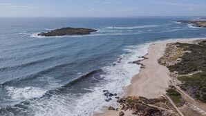 Un paisaje costero con una playa arenosa, afloramientos rocosos y una vista despejada del océano.