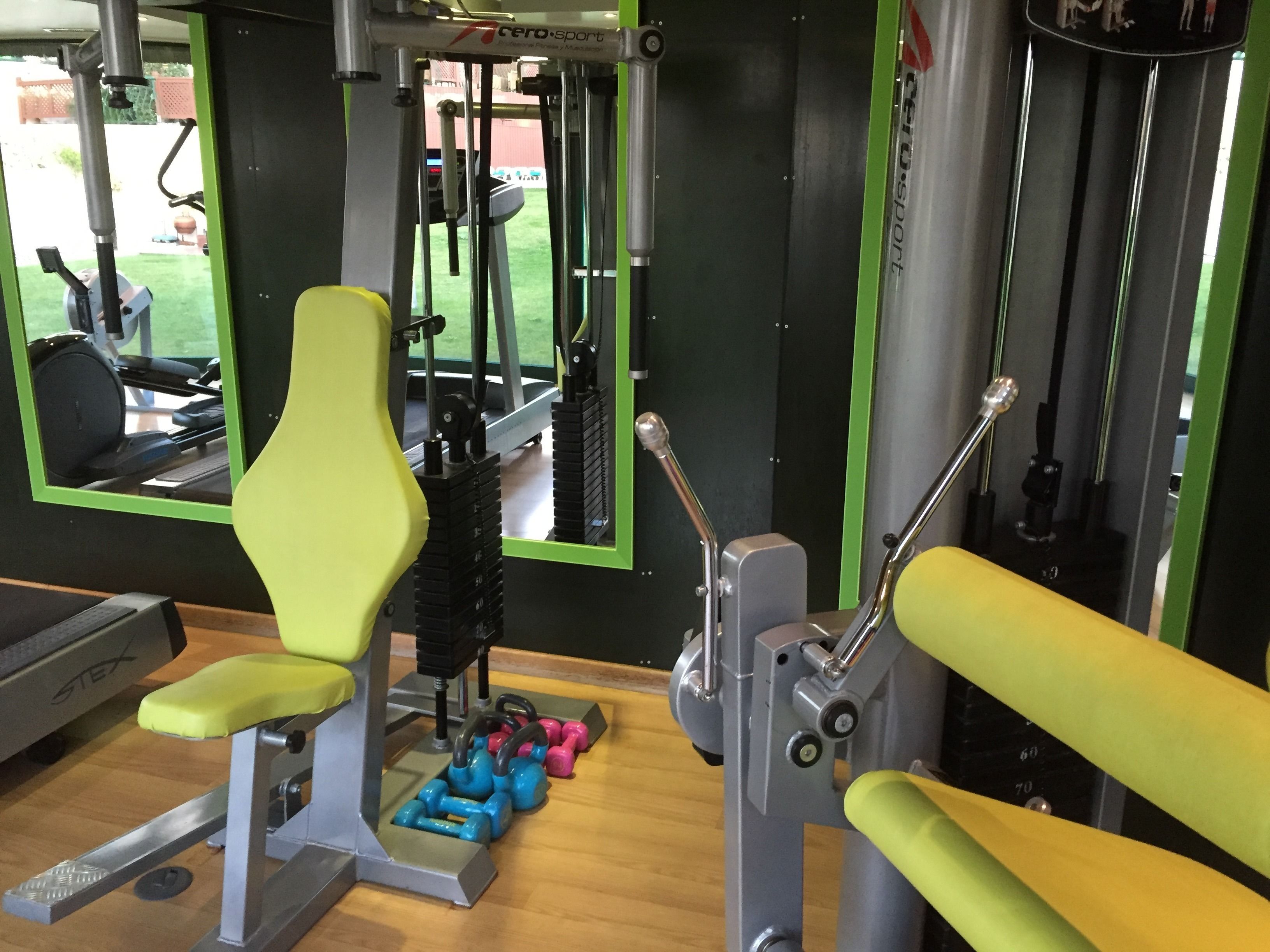 Een fitnessruimte met trainingsapparatuur, waaronder een bank, gewichten en een krachttrainingapparaat.