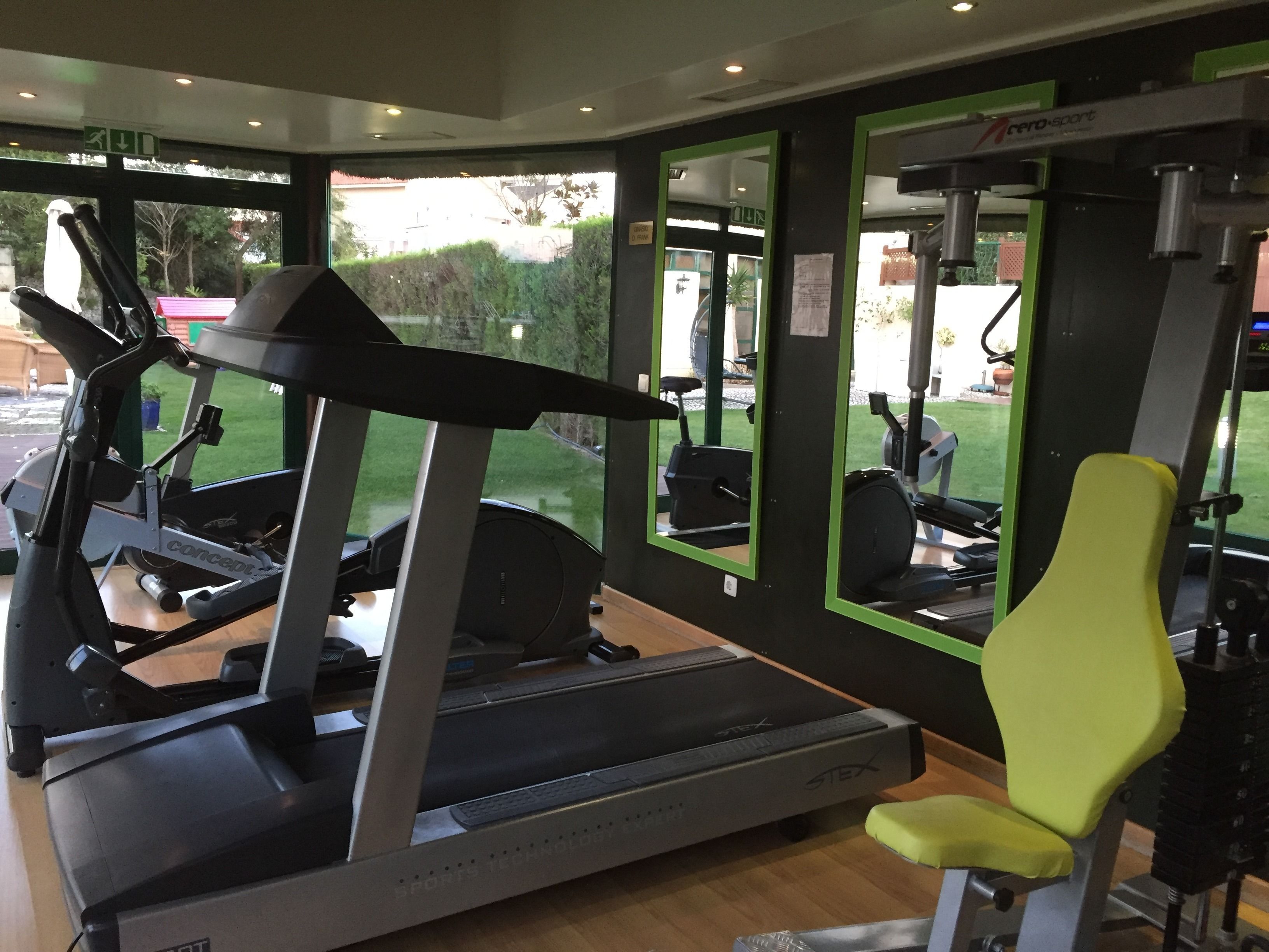Une salle de sport équipée d’un tapis de course, d’un vélo d’exercice et d’une chaise jaune.