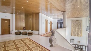 Un vestíbulo espacioso con techo alto, alfombra estampada y una escalera con barandilla.